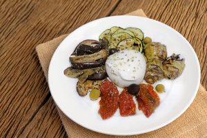 Grilled chicken on a white plate with tomatoes, salad, onion, ch
